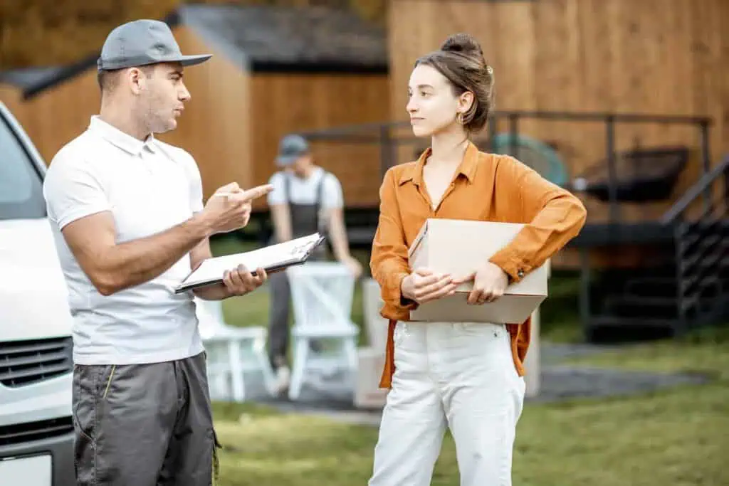 a woman talks seriously with a mover in a yard