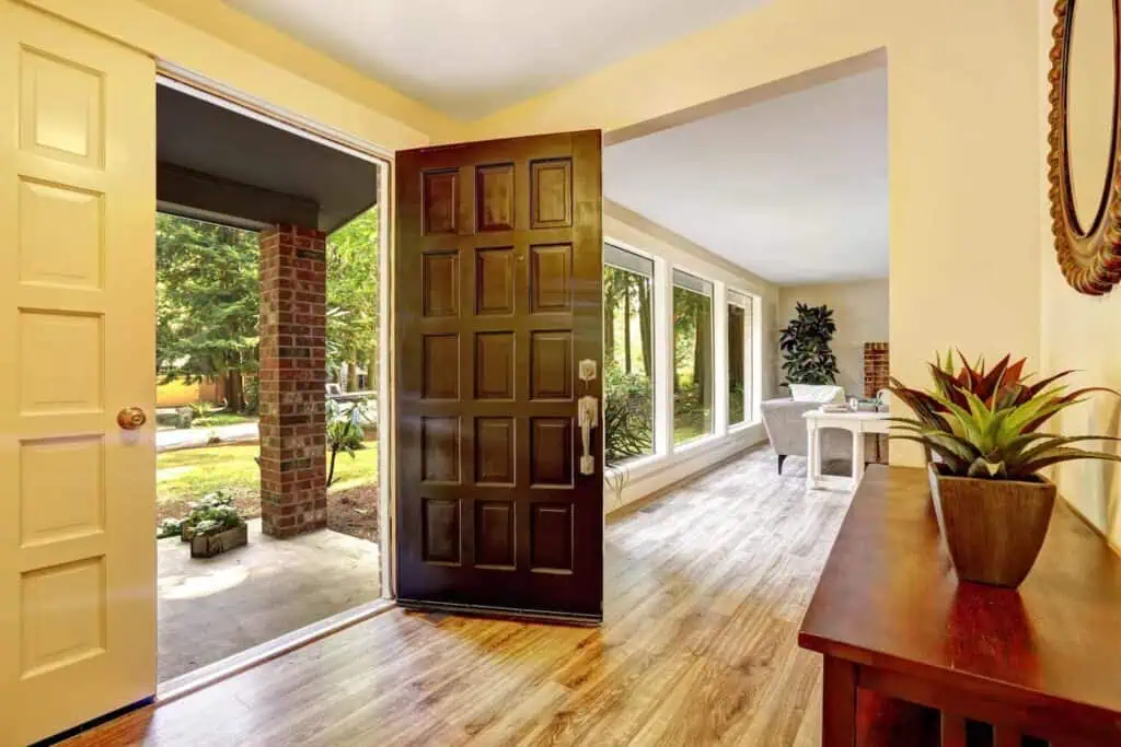 an open door leads out to a yard from a decorated entryway of a home