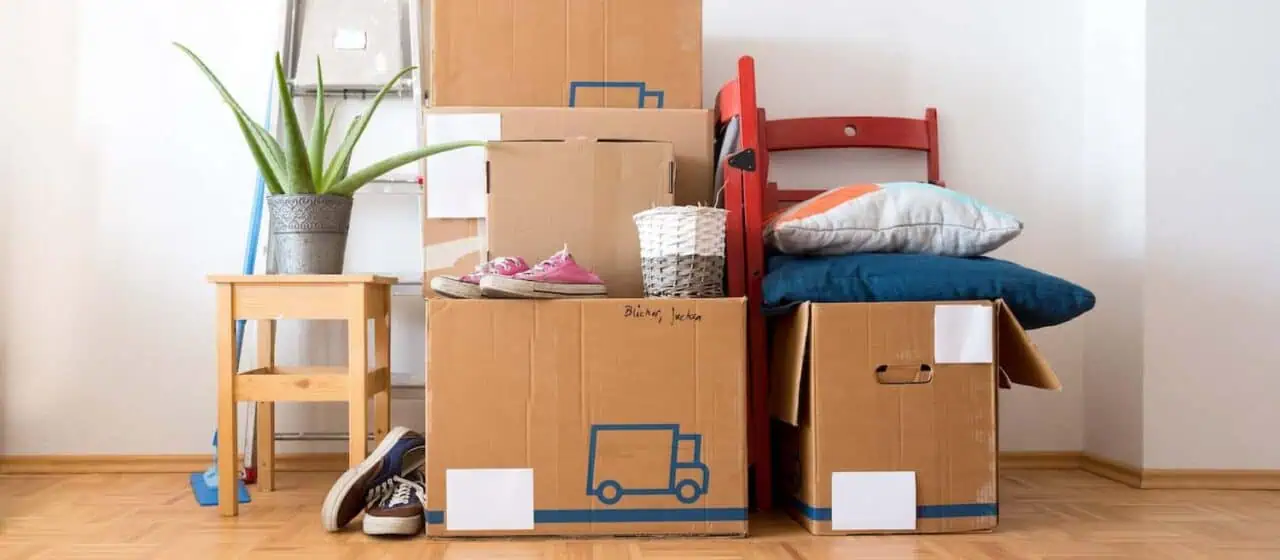 A pile of boxes filled with various items. Shoes and pillows are stacked on top of some of them