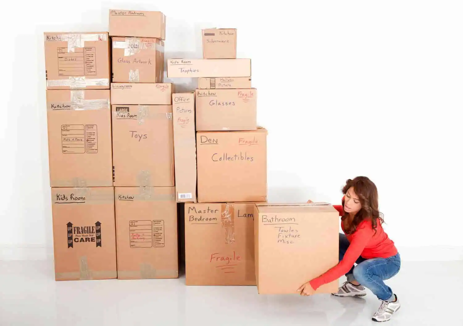A woman picks up a large box that's next to a section of moving boxes in all different sizes