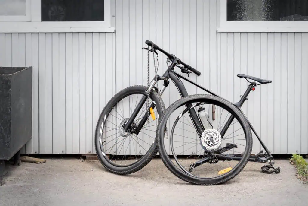 A disassembled bicycle sits against a wall