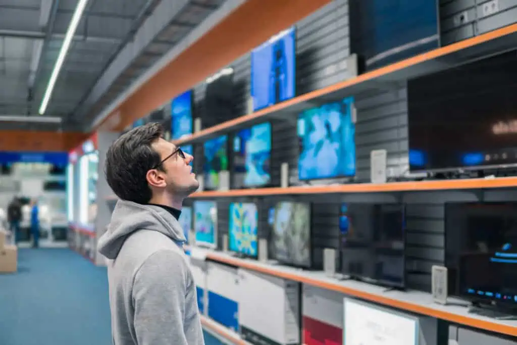 a man looks at different types of TVs in a store