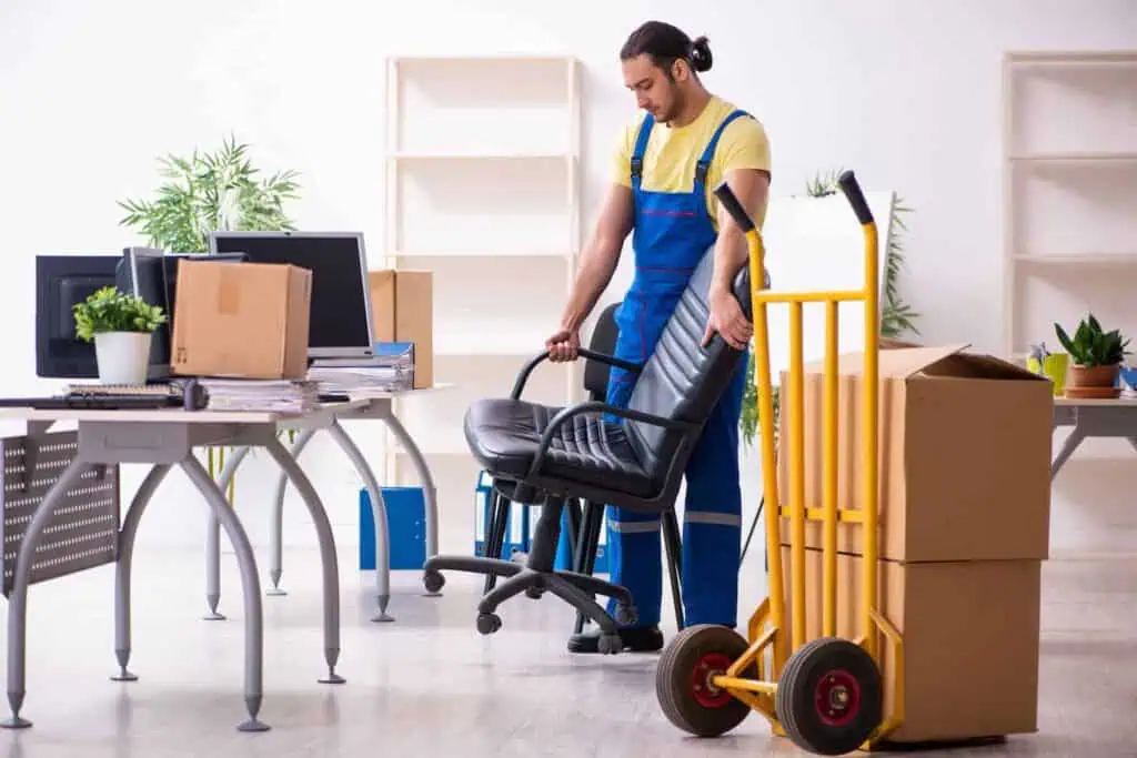 A mover picks up an office chair to prepare it for wrapping and packing
