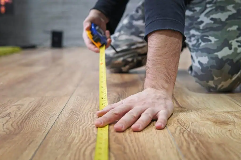 A man measuring part of a room with a measuring tape
