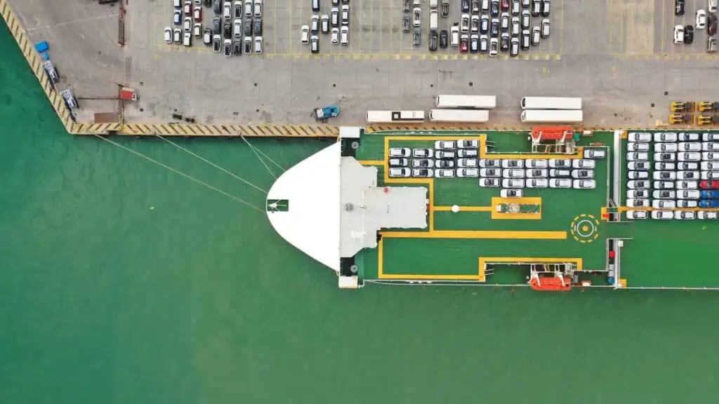 Cars are loaded onto a large ship for transport overseas