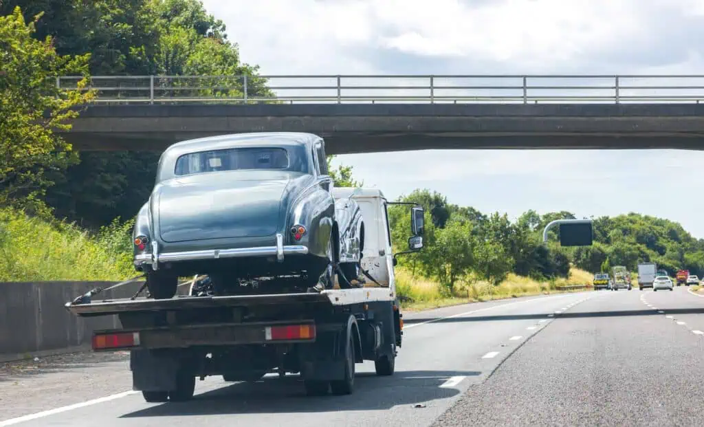 A vintage car on a tow truck being transported