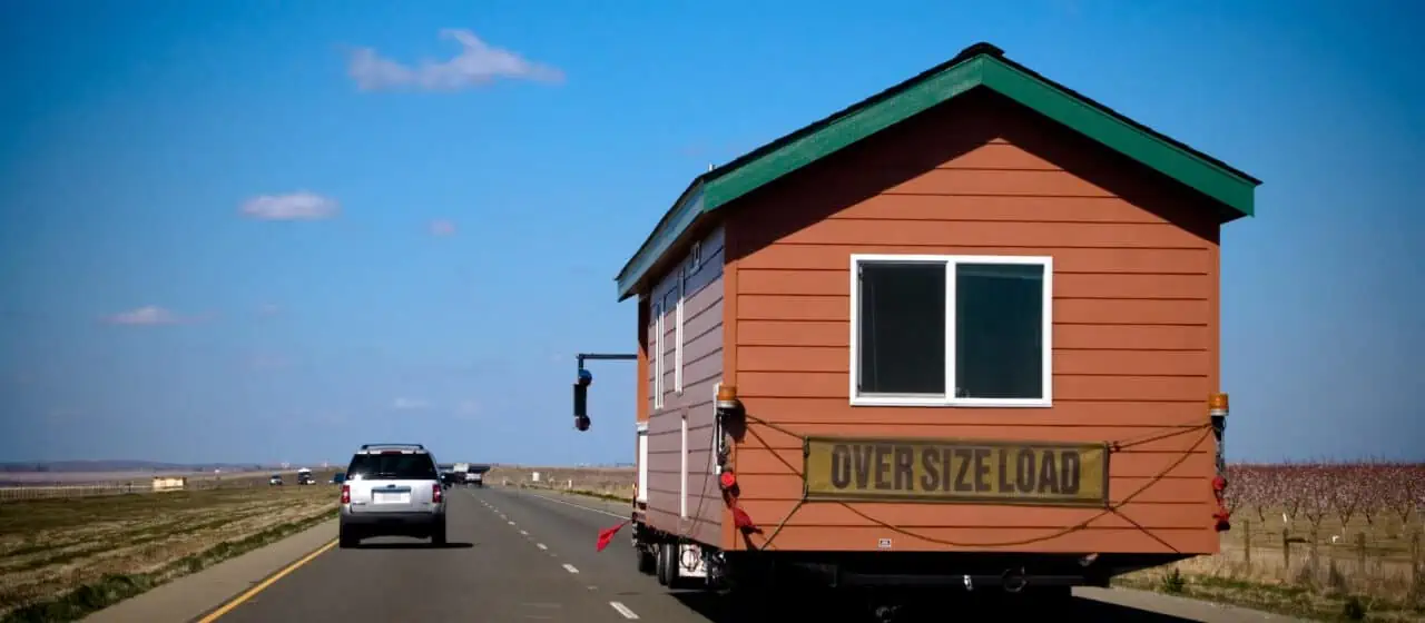 a truck driving down an open highway towing a mobile home for a move