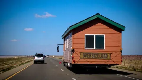 a truck driving down an open highway towing a mobile home for a move