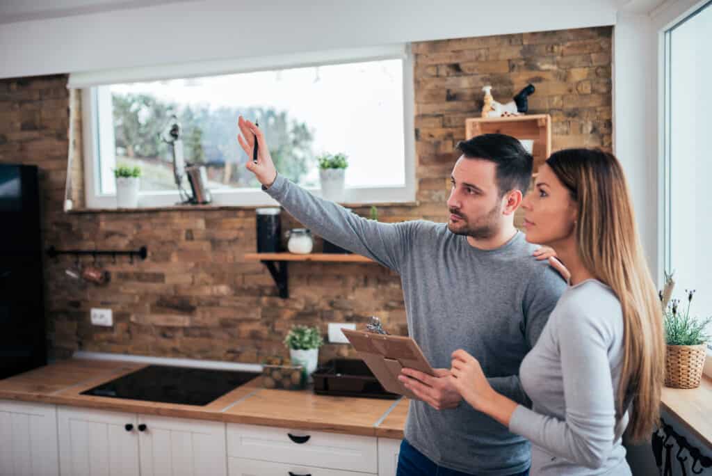 a man and a woman look over a kitchen in preparation for remodeling it