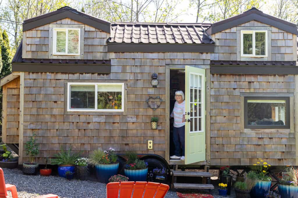 A woman leans out of the doorway of her tiny home