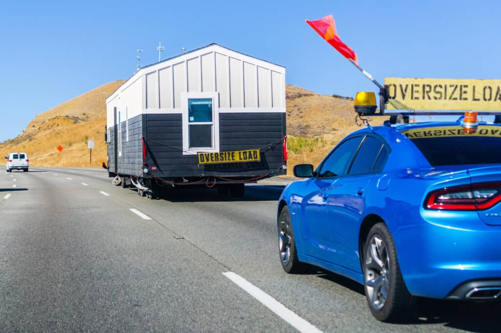 a manufactured house being moved via truck and car escort 