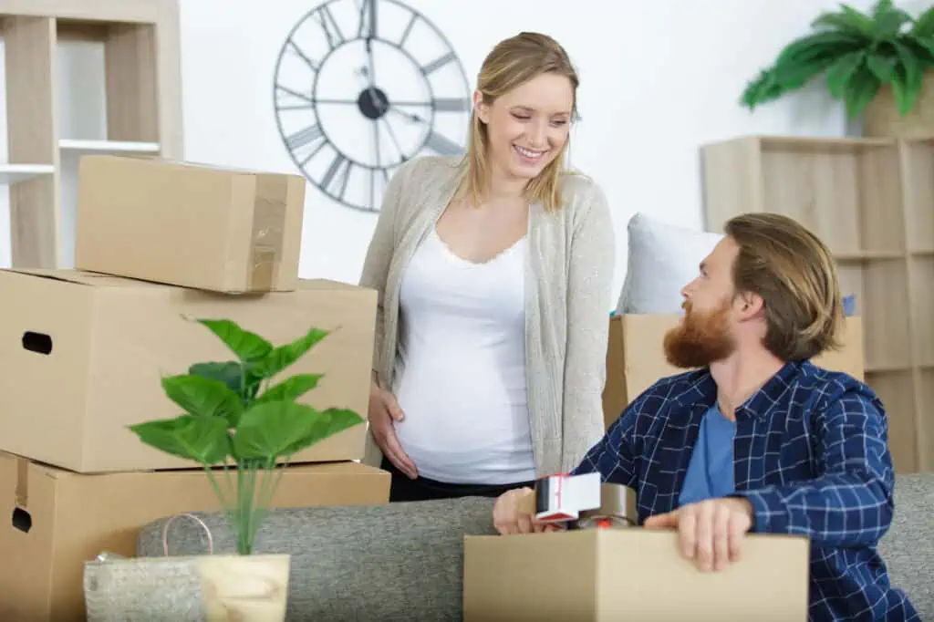 pregnant couple talks while packing boxes for an upcoming move