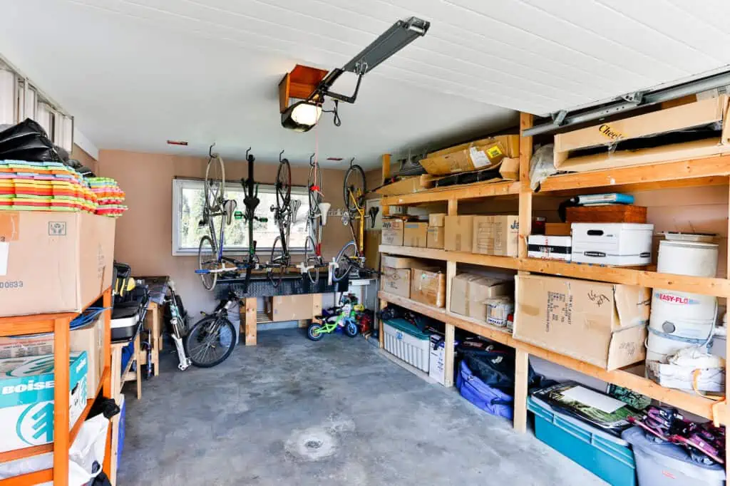 a garage converted into storage for bikes, a tricycle, and boxes of household items.