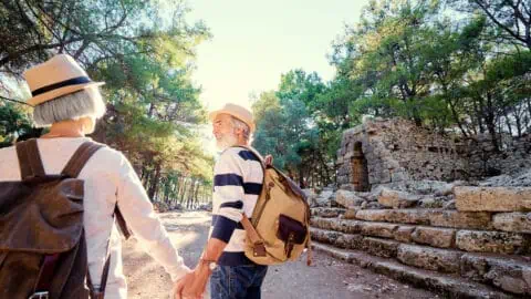 a senior couple holding hands as they walk through stone ruins