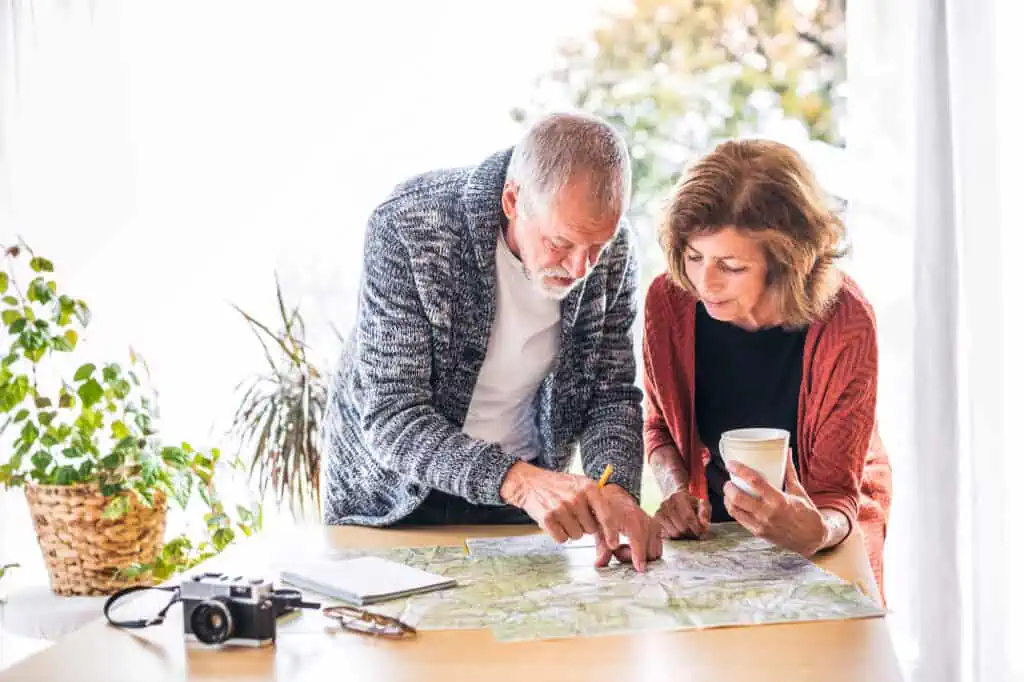 a senior couple plans their retirement abroad by looking over a map
