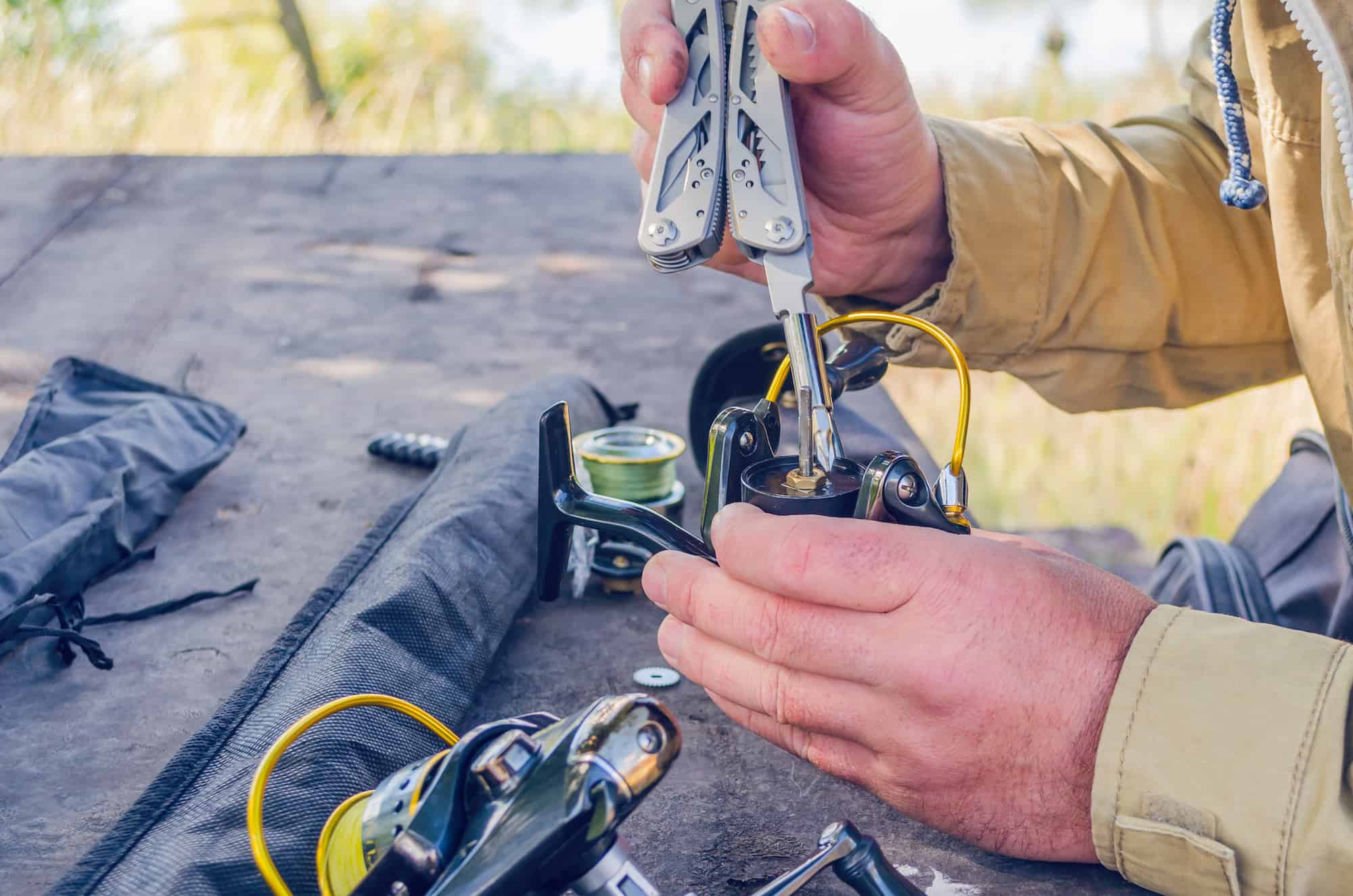 a man takes apart a fishing real at a table to check for damage and perform maintenance 