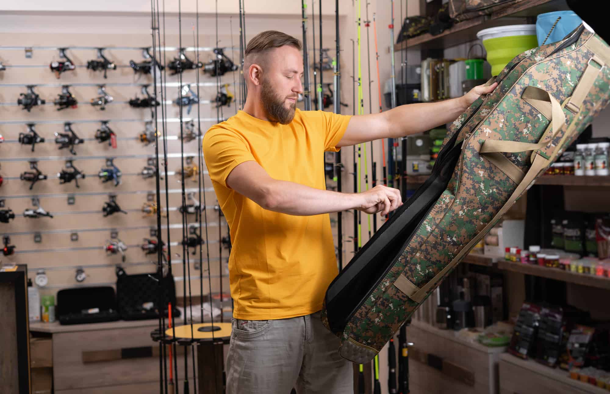 a man looks over a camo-patterned fishing rod case. 