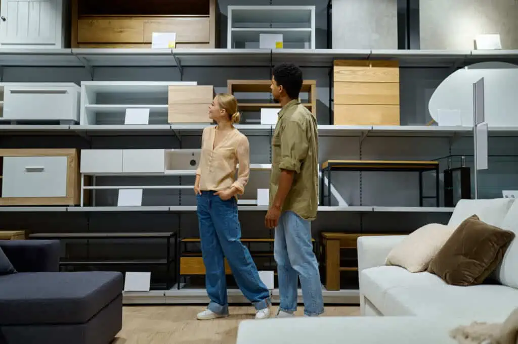 a couple walking through a section of a furniture store, looking at shelving and couch options