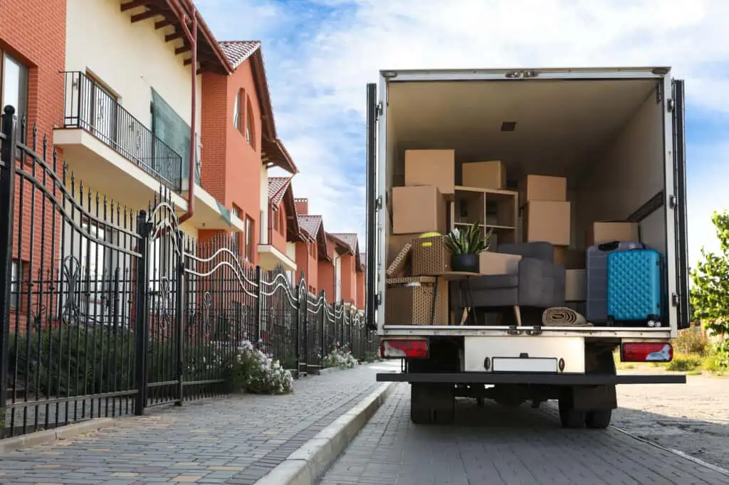 a moving truck full of boxes and furniture parked in front of a line of homes