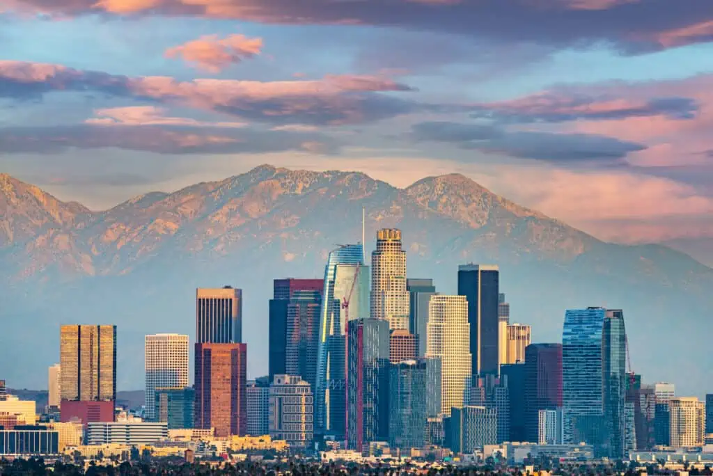 a view of the Los Angeles skyline at sunset. Behind the skyscrapers are the San Gabriel mountains. 