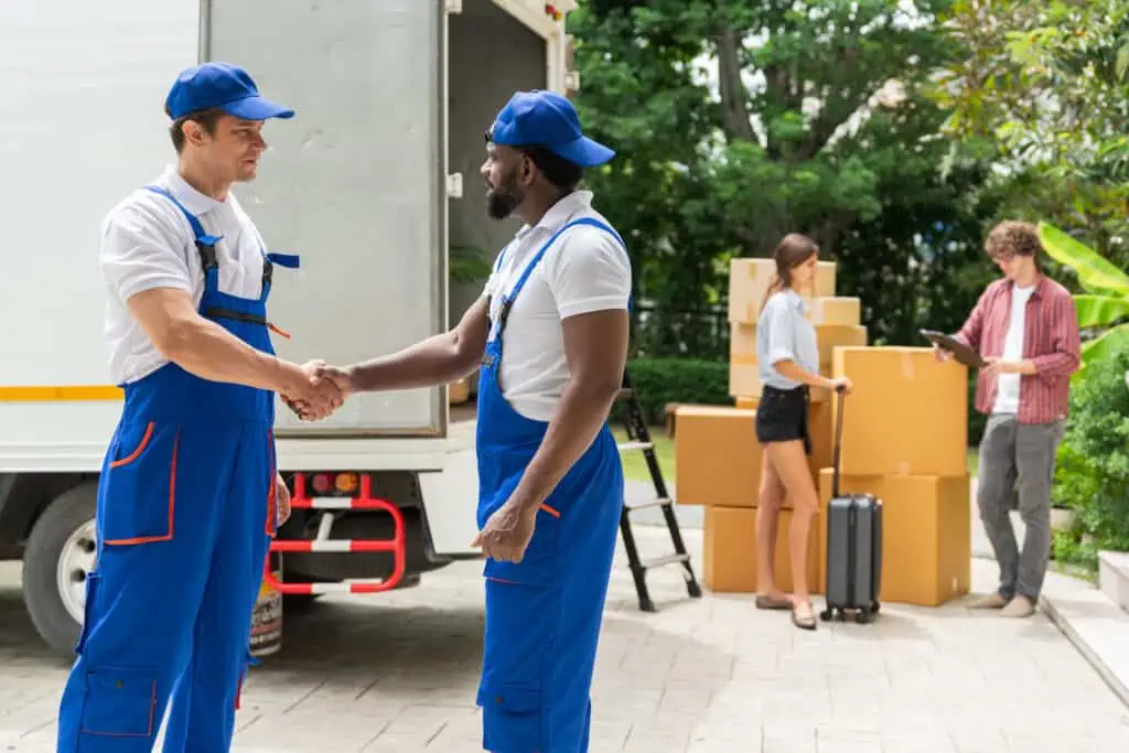two movers shake hands and talk in front of customers 