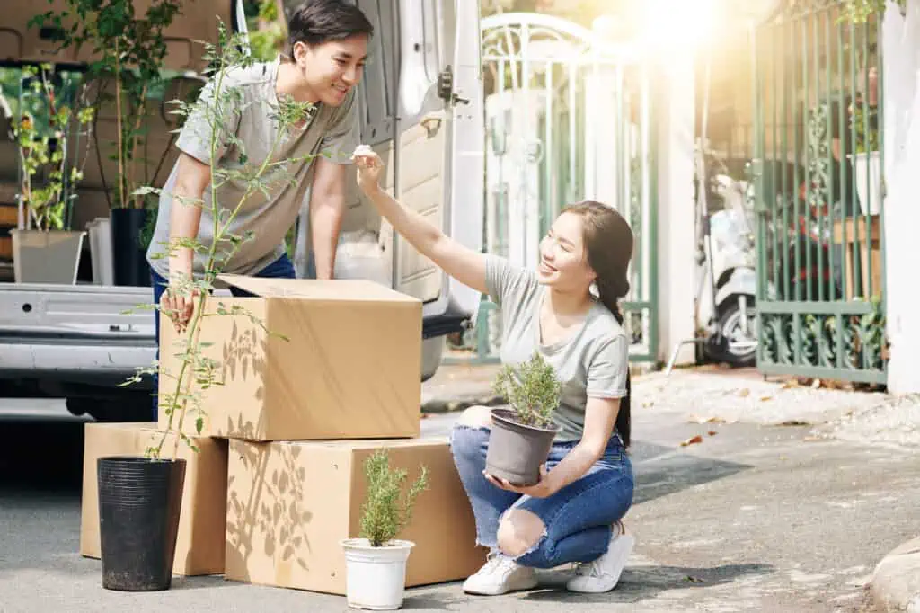 a man and a woman check plants they've unloaded from a rented moving van