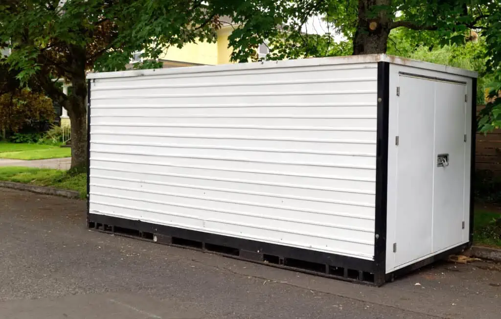 a white moving container sitting on a residential street, waiting to be loaded 