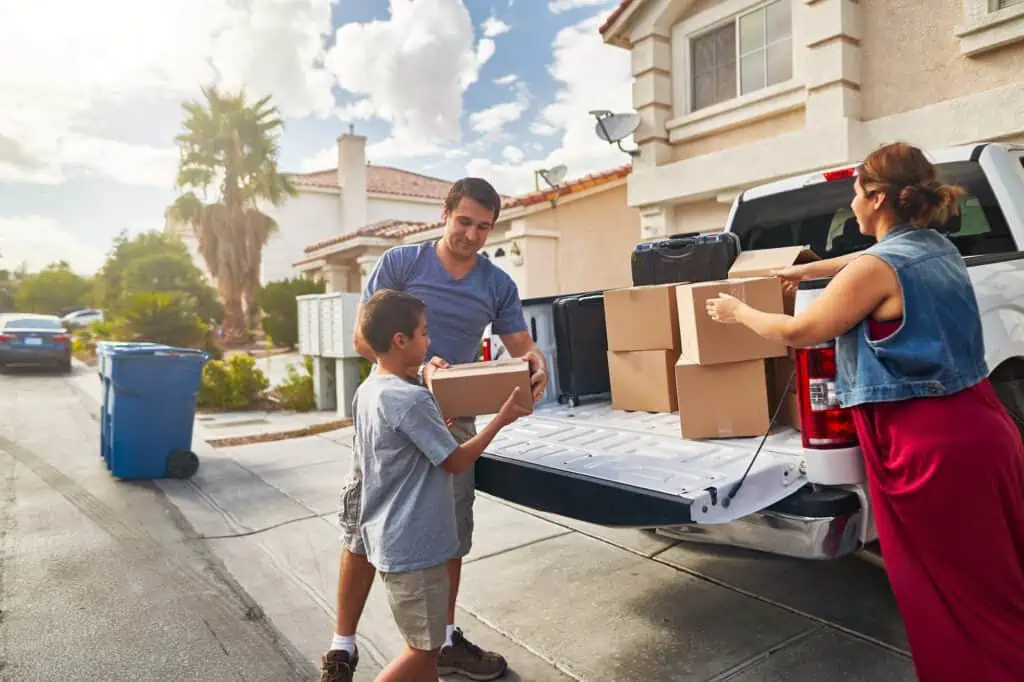 a family packs boxes and suitcases into the bed of their truck