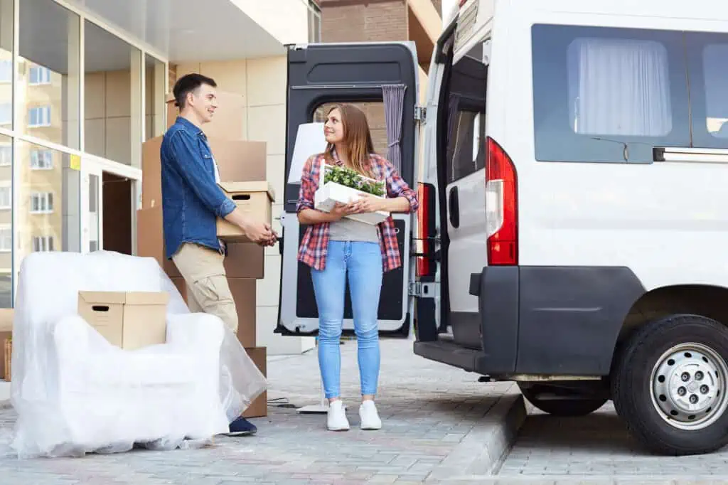 A man and a woman loading boxes and small furniture items into a van