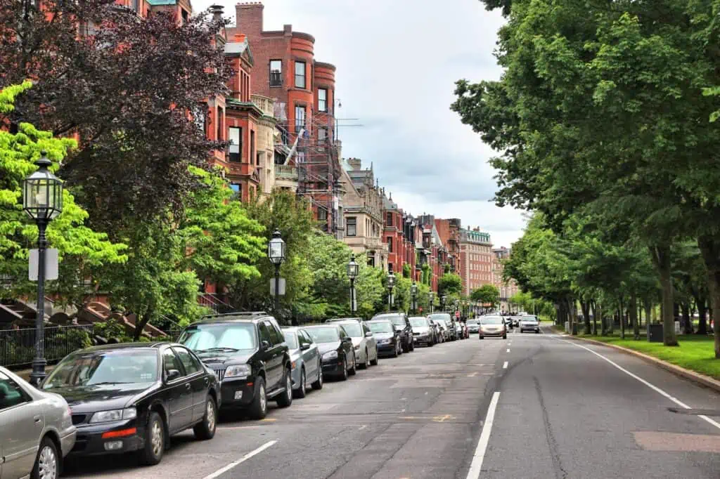 a neighborhood in Boston with brick homes and the street lined on one side with parked cars