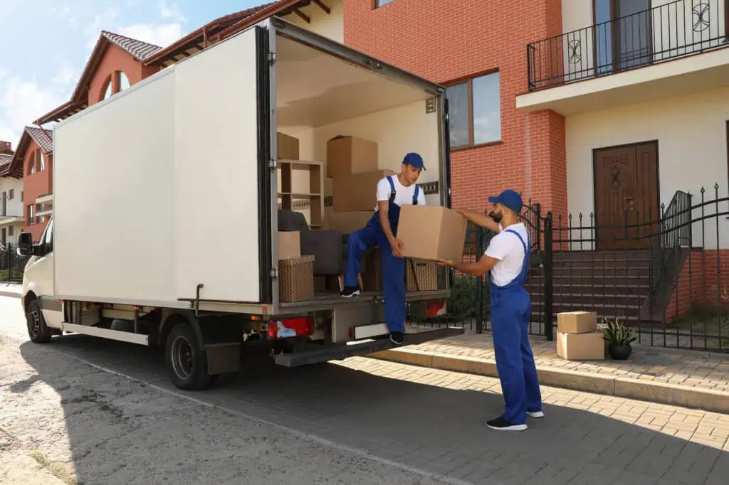movers unloading boxes from a moving truck that's parked on a residential street