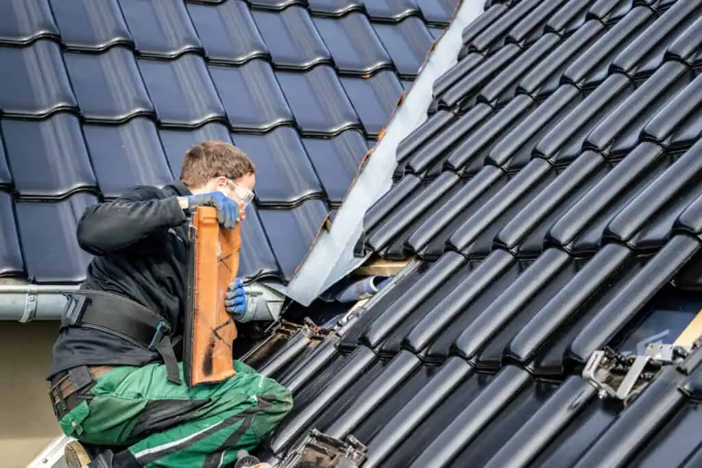a technician removes tiles on a roof to make way for solar panel rigging