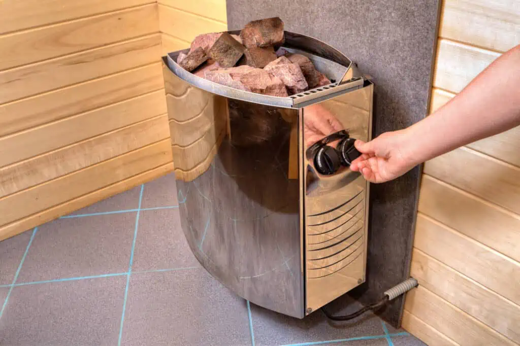 a person turns on a sauna's electric heater to test it