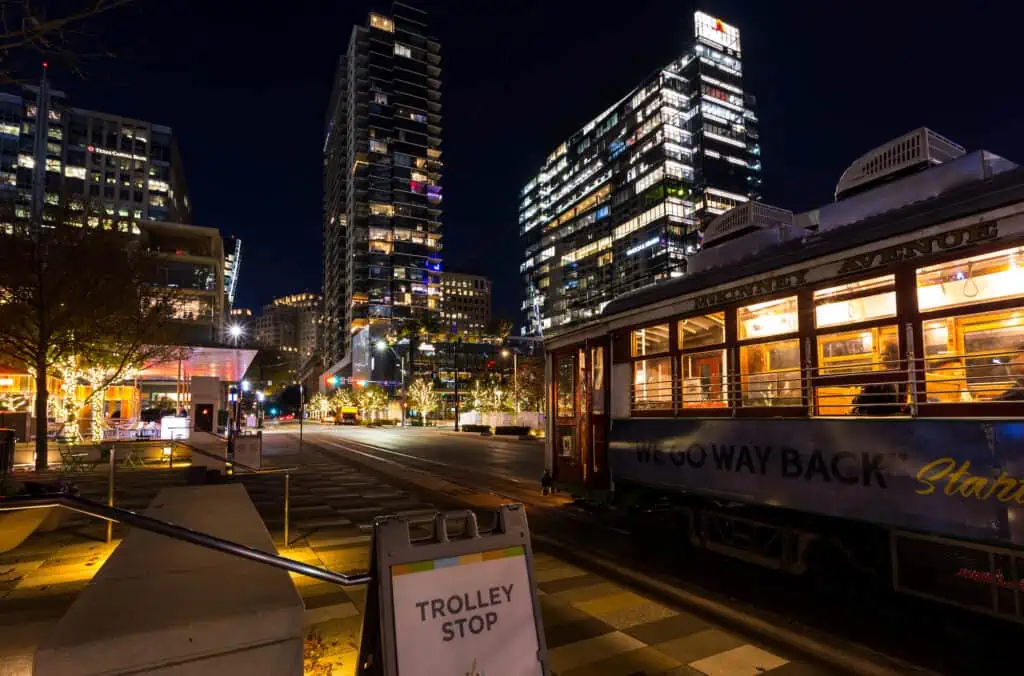 a view of Uptown Dallas at night, along with the famous vintage trolley