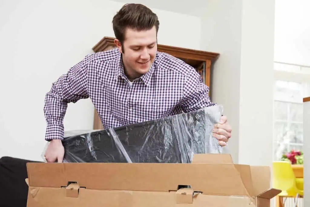 A man puts a tv with a screen protector into a box