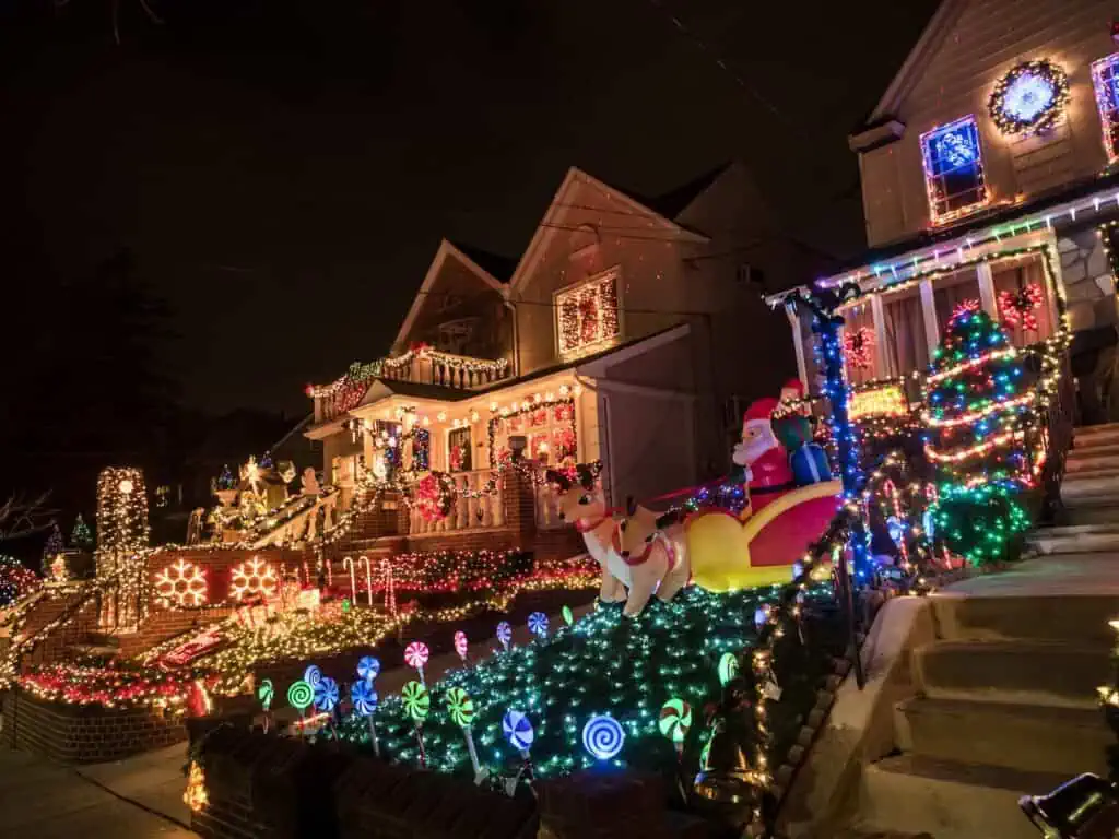 a view of houses at night lit up with christmas lights during the annual display in the dyker heights neighborhood of brooklyn