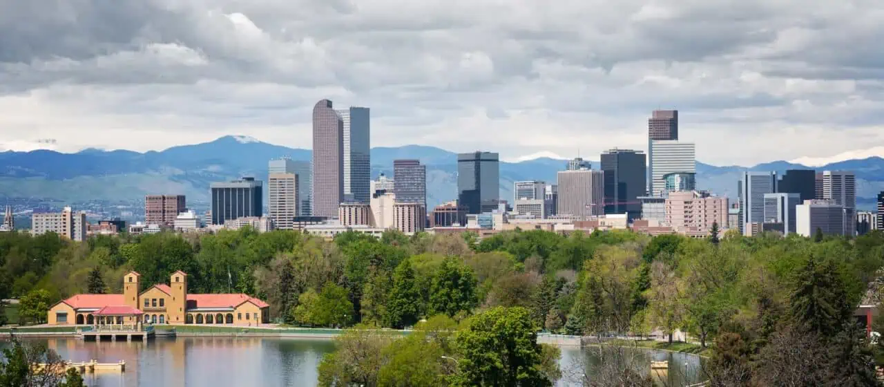 a view of downtown denver's skyline, a lake and park can be seen in the foreground