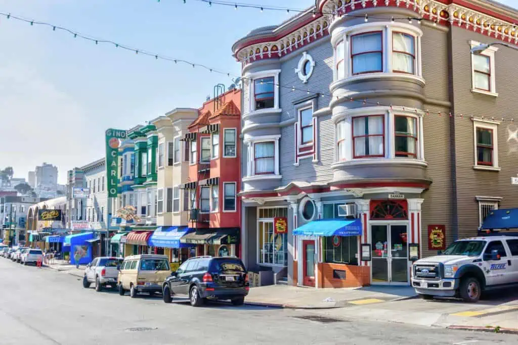 a street in the Marina neighborhood of San Francisco, showing colorful Victorian style facades and some cafes