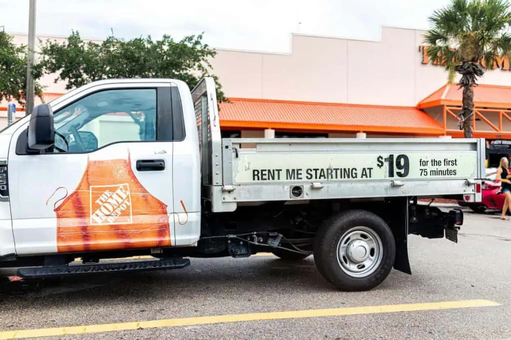 a home depot flatbed truck available for rent, parked in the parking lot in front of a home depot store