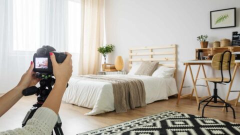 someone sets up a camera on a tripod to take a photo of a bedroom