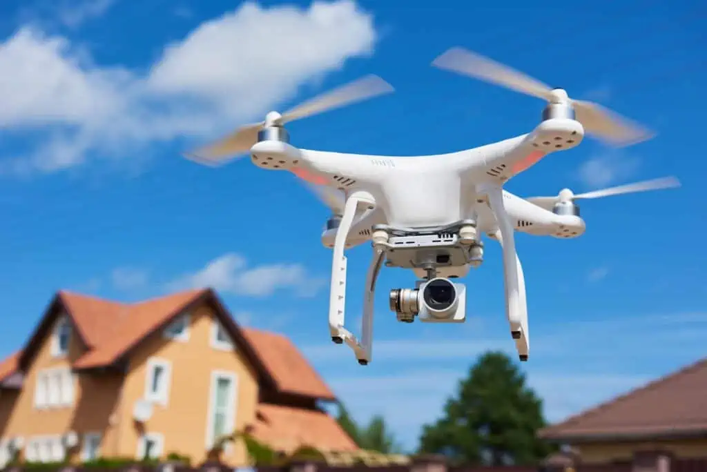 a drone with a camera attachment hovers in front of a house 