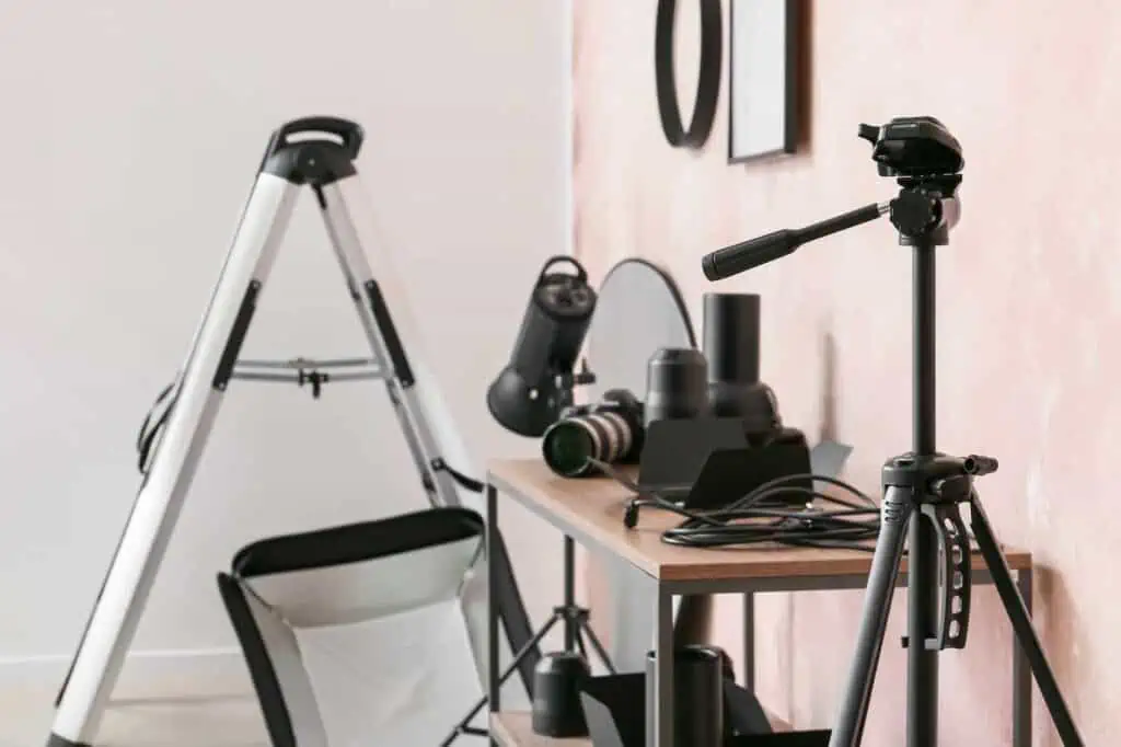 Photography equipment, including dsl camera, tripod, lenses, and lighting are all displayed on a shelf
