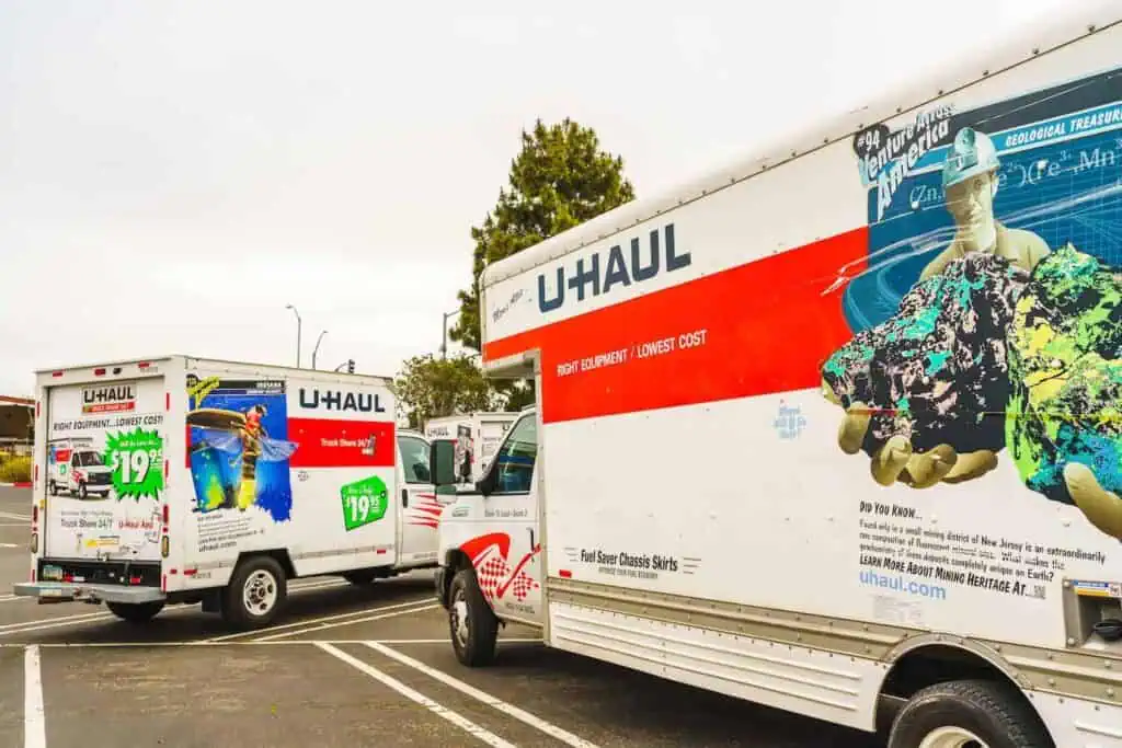 two uhaul trucks pull out of a parking low