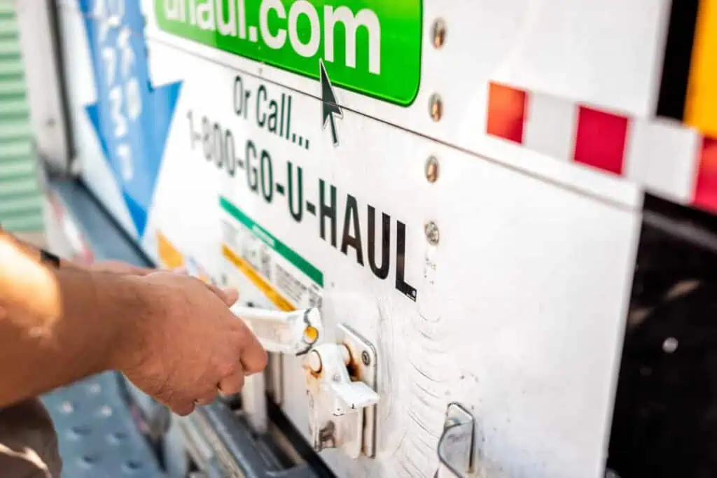 a person shuts and closes the back door to a uhaul truck