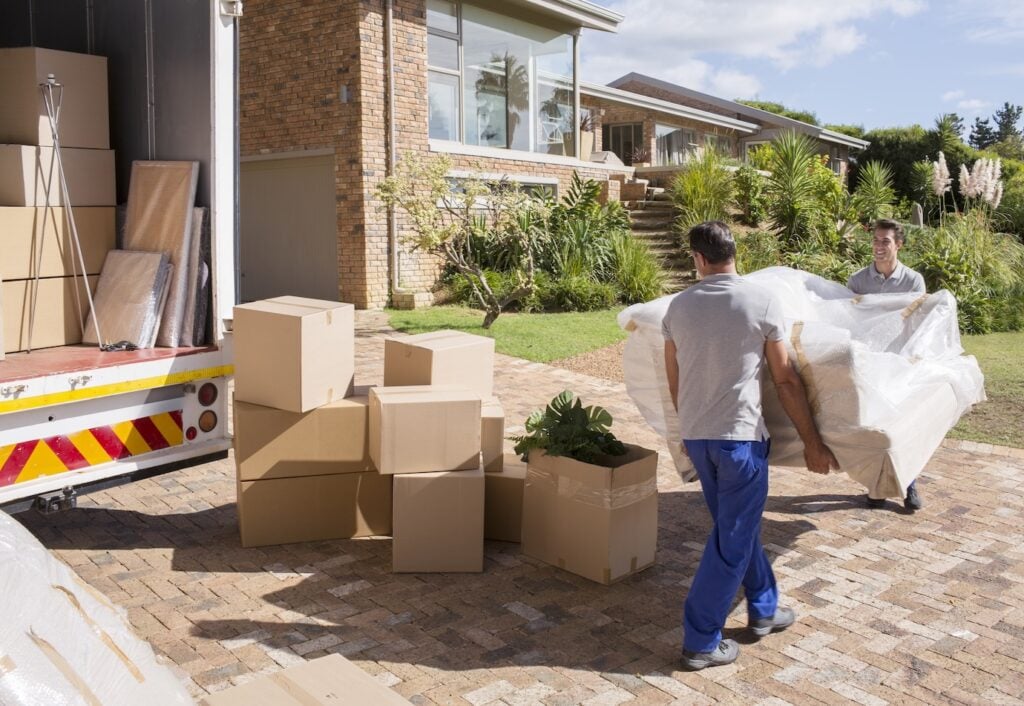 Movers carrying sofa from house to moving truck