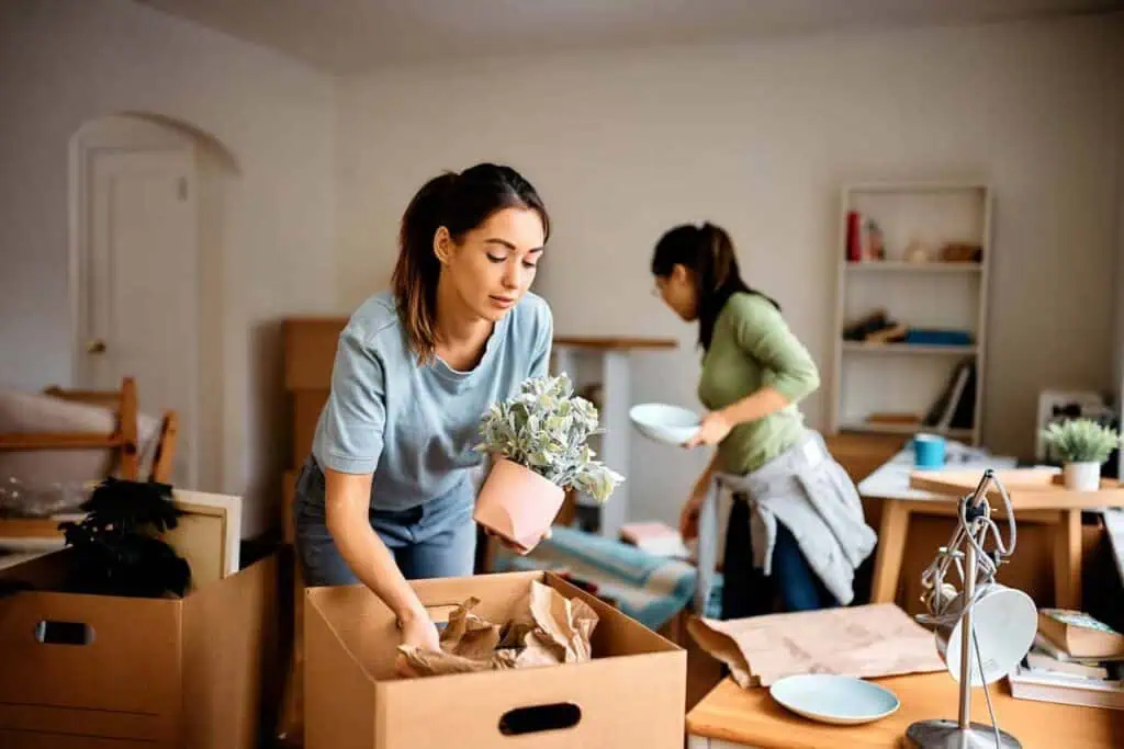 Two women work together to pack up a room into moving boxes