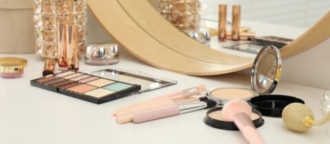 an image of makeup and accessories on a vanity table with a mirror