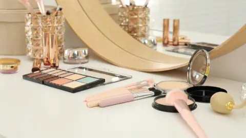 an image of makeup and accessories on a vanity table with a mirror