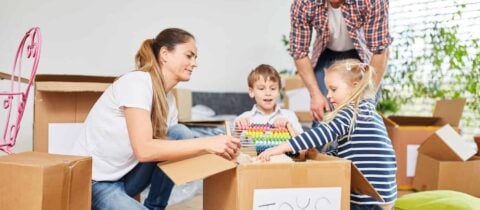 A family helps their children pack toys into a box