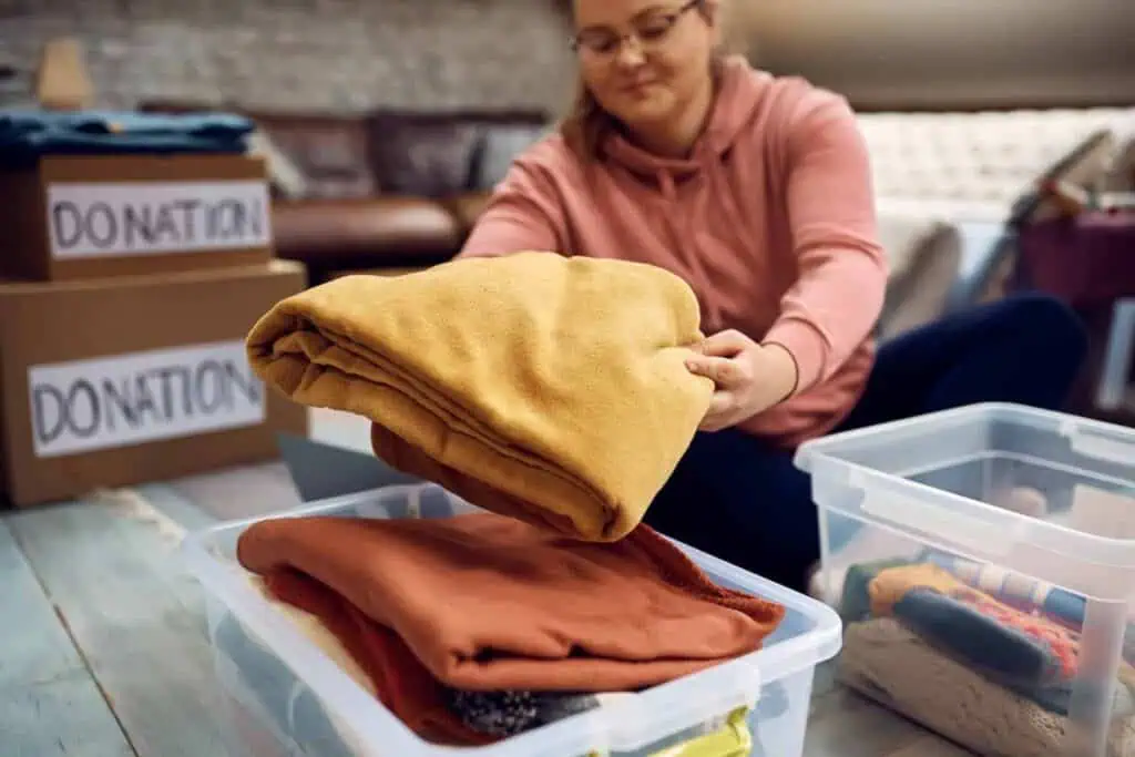 A woman sorts items into various boxes, some labeled "donation" as she declutters her space